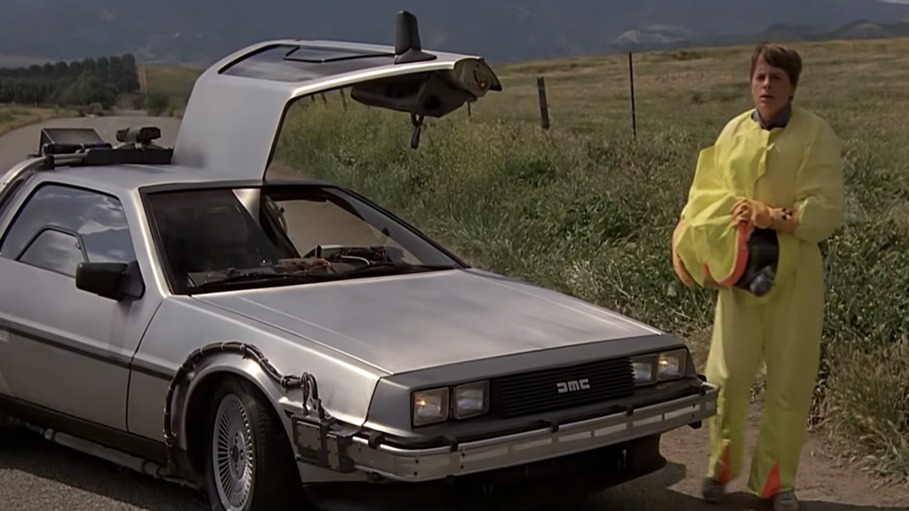 Michael J. Fox as Marty McFly standing next to the DeLorean time machine in Back to the Future.