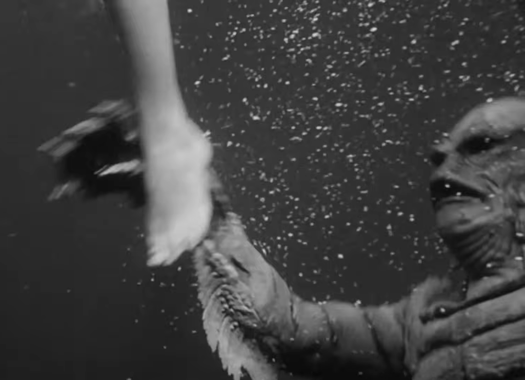 The Gill-Man reaches for a leg underwater (Creature from the Black Lagoon)