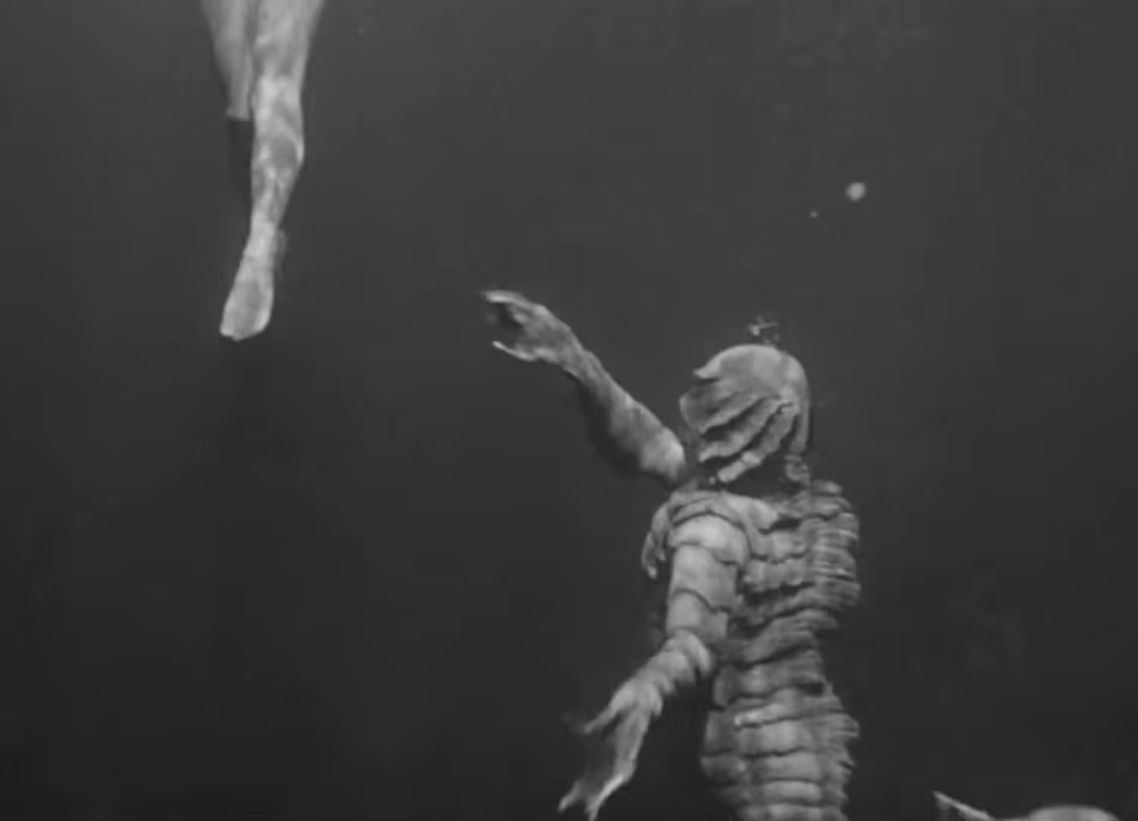 The Gill-Man reaches for a leg underwater (Creature from the Black Lagoon)